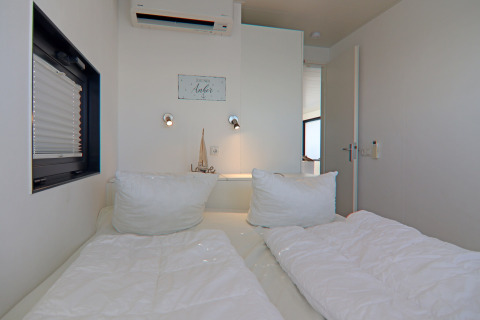 Dormitorio de la casa flotante 'Family & Friends LP 4', decoración minimalista y ropa de cama blanca en Alemania.