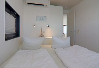 Chambre à coucher de la péniche 'Family & Friends LP 4', décor minimaliste, literie blanche confortable en Allemagne.