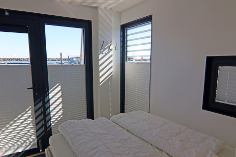 Dormitorio con grandes ventanales y vistas al agua en la Houseboat Family & Friends LP 4 en Alemania.