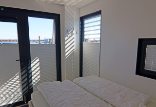 Dormitorio con grandes ventanales y vistas al agua en la Houseboat Family & Friends LP 4 en Alemania.