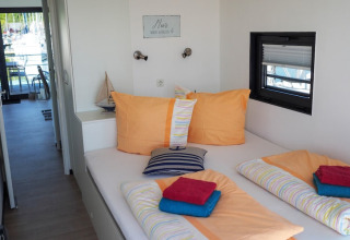 Houseboat bedroom with colorful bedding, nautical-themed decor, and a view of a marina through the window.