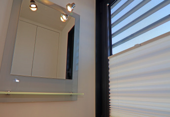 Espejo con luces y una ventana con persianas en el Houseboat Family & Friends LP 4 en Alemania.