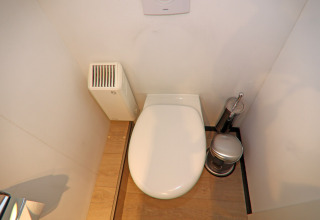 Moderne husbådstoilet med trægulv, radiator og toilettilbehør, set ovenfra på Houseboat Family & Friends LP.
