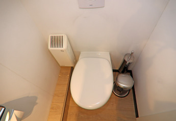 Moderne husbådstoilet med trægulv, radiator og toilettilbehør, set ovenfra på Houseboat Family & Friends LP.