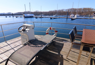 View from Houseboat 'Family & Friends LP 4' in Germany with sun lounger, table, and marina in the background.