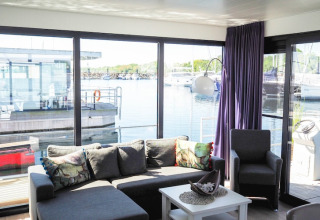 Bright, modern living room on a houseboat with large windows and marina views in Germany.
