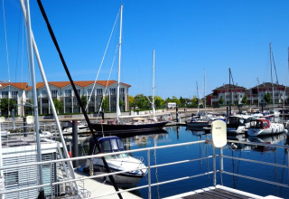 Vista desde la casa flotante Family & Friends LP 4 al puerto deportivo con veleros y apartamentos modernos en Alemania.