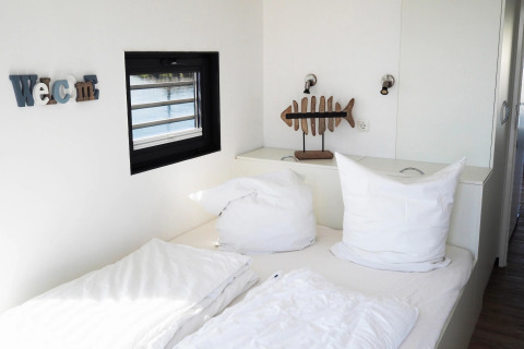 Dormitorio moderno y luminoso en una casa flotante en Alemania con cama doble y decoración de pez.