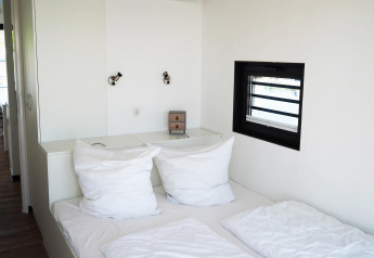 Modern bedroom on Houseboat Family & Friends with Dog, white bedding and small window in Germany.