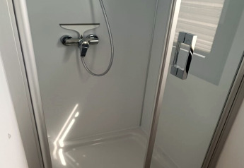 Modern shower cabin with glass door and chrome handle on the Floating 44 houseboat in Germany.