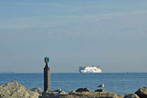 Vue de la péniche Floating 44 en Allemagne, avec un ferry Stena Line au loin et des rochers au premier plan.