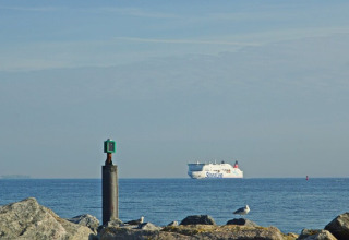 Vue de la péniche Floating 44 en Allemagne, avec un ferry Stena Line au loin et des rochers au premier plan.
