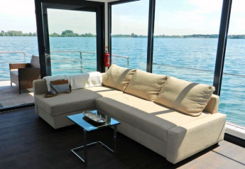 Bright and modern living area on a houseboat with large windows overlooking the water and deck.