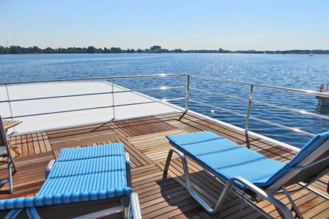 Solterrasse på husbåden Floating 44 med to liggestole og udsigt over søen ved solskin i Tyskland.