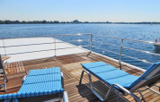 Sun deck of houseboat Floating 44 with two blue lounge chairs overlooking a lake in sunny Germany.