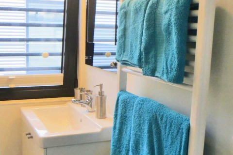 Bagno moderno su una houseboat con lavabo bianco, dispenser in metallo e asciugamani blu su portasciugamani.