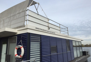 Flydende husbåd med moderne design og redningskrans ved www.hausboot-sonneninsel.de i Tyskland.