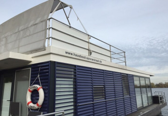 Péniche moderne avec bouée de sauvetage et terrasse sur www.hausboot-sonneninsel.de, en Allemagne.
