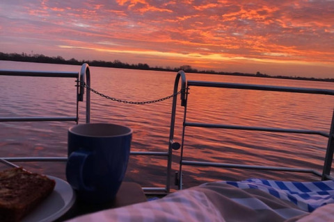 Solopgang over søen set fra en husbåd med morgenmad, kaffe og smuk himmel i Tyskland.