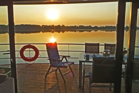 Vista dalla houseboat 'Floating 44 / Boot 1' al tramonto, con sedie e tavolo sul ponte in Germania.