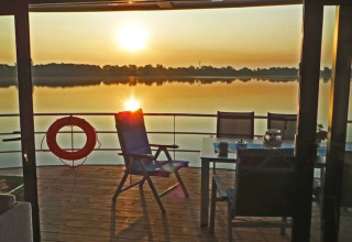 Uitzicht vanop het huisboot 'Floating 44 / Boot 1' bij zonsondergang, met stoelen en tafel op het dek in Duitsland.