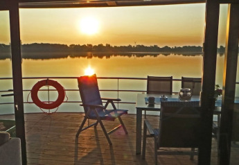 Vue depuis la péniche 'Floating 44 / Boot 1' au coucher du soleil, avec chaises et table sur le pont en Allemagne.