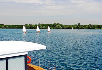 Vue depuis la péniche Floating 44 sur des voiliers au lac et une végétation luxuriante, Allemagne.