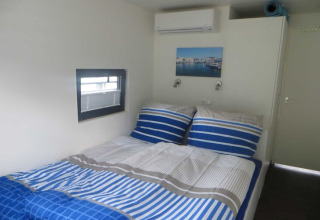 Camera da letto sulla houseboat Floating 44 / Boot 5 in Germania con lenzuola blu a righe e finestra.