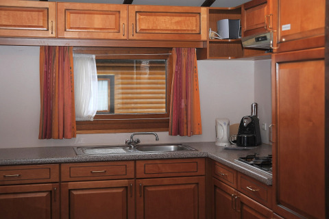 Knusse houten keuken met raam, oranje gordijnen en toestellen in Chalet Waldferienpark Gerolstein.