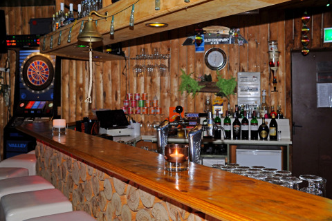 Rustieke houten bar met een dartautomaat, tapkranen en flessen in Waldferienpark Gerolstein 2, Duitsland.
