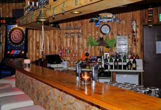 Rustieke houten bar met een dartautomaat, tapkranen en flessen in Waldferienpark Gerolstein 2, Duitsland.