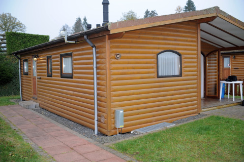 Afbeelding van een chalet in Waldferienpark Gerolstein 2, Duitsland, met houten bekleding en terras.