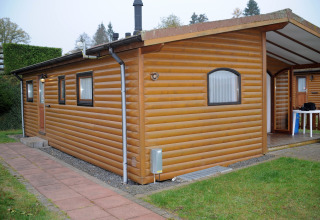 Afbeelding van een chalet in Waldferienpark Gerolstein 2, Duitsland, met houten bekleding en terras.