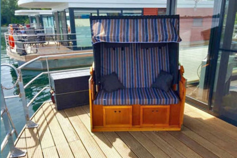 Buitendek van een woonboot met gestreepte bank en glazen wand bij Floating 44 in Duitsland.