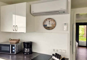 Moderne kitchenette met magnetron, koffiezetapparaat en klok op een woonboot in Duitsland.