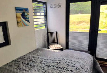 Slaapkamer op woonboot Floating 44 / Boot 7 in Duitsland met tweepersoonsbed, ramen en uitzicht.