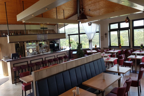 Modern restaurantinterieur met bar en grote ramen in Waldferienpark Gerolstein 2, Duitsland.