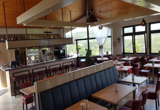 Modern restaurantinterieur met bar en grote ramen in Waldferienpark Gerolstein 2, Duitsland.