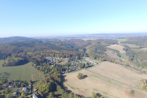 Luchtfoto van Waldferienpark Gerolstein 2 chalet in Duitsland, omgeven door heuvels en open velden.