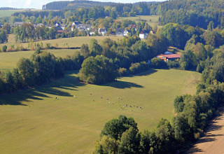 Uitzicht op groene weiden, bomen en huizen bij Waldferienpark Gerolstein 2 in Duitsland.