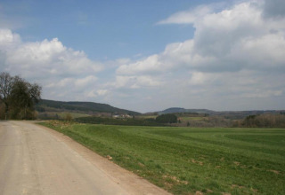 Landschapsbeeld nabij Waldferienpark Gerolstein 2 in Duitsland met weg, groene velden en verre heuvels.