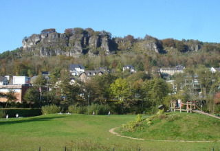 Zicht op groene weides en een dorp onder een rotsheuvel, genomen vanuit Waldferienpark Gerolstein 2, Duitsland.