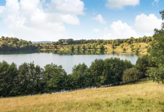 Uitzicht op een meer met groene heuvels en bomen bij Waldferienpark Gerolstein 2, Duitsland.