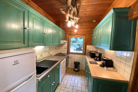 Rustieke houten keuken met groene kasten en moderne apparatuur in 'LE FISHING LODGE Wooden chalet with Nordic Bath', Frankrijk.