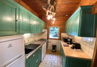 Cucina rustica in legno con mobili verdi ed elettrodomestici moderni presso 'LE FISHING LODGE Wooden chalet with Nordic Bath', Francia.