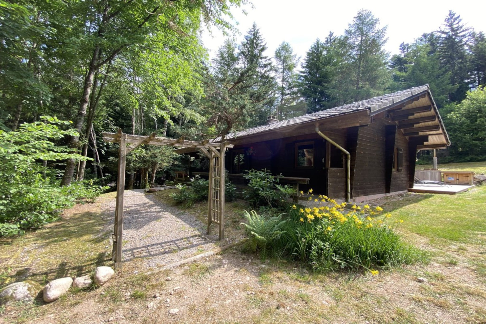 Buitenaanzicht van LE FISHING LODGE, houten chalet met Scandinavisch bad, omgeven door bos in Frankrijk.