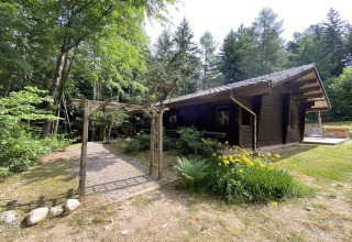 Buitenaanzicht van LE FISHING LODGE, houten chalet met Scandinavisch bad, omgeven door bos in Frankrijk.