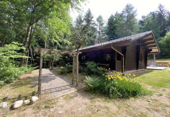 Buitenaanzicht van LE FISHING LODGE, houten chalet met Scandinavisch bad, omgeven door bos in Frankrijk.