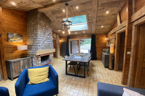 Sfeervol houten interieur in LE FISHING LODGE chalet met open haard, eettafel en dakraam in Frankrijk.