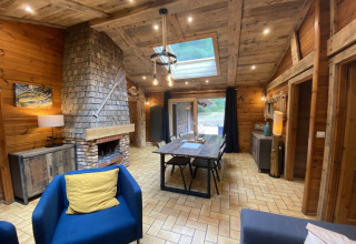 Gezellige houten woonkamer van LE FISHING LODGE chalet met haard, eettafel en lichtkoepel in Frankrijk.